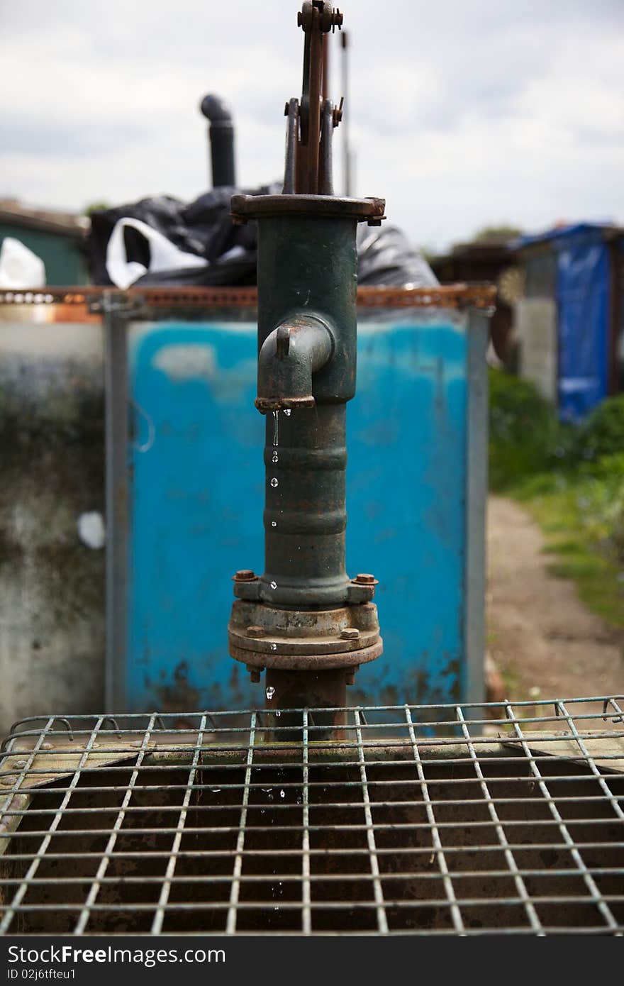 A Water-pump at an allotment taken at high speed to freeze the falling water. A Water-pump at an allotment taken at high speed to freeze the falling water