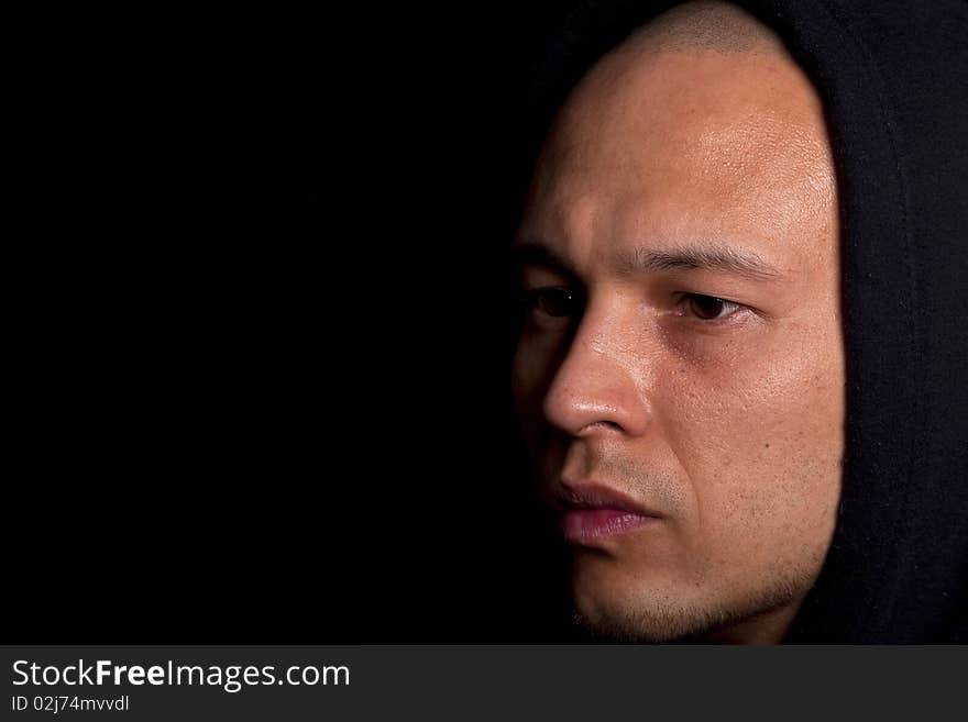 Stylish young man with hoddie over a black background.