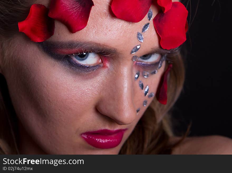 Young fresh woman with an extreme and glamorous makeup and roses on her face. Young fresh woman with an extreme and glamorous makeup and roses on her face.