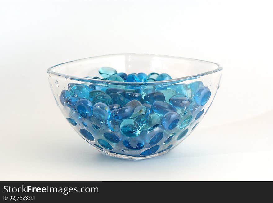 Brilliant blue stones from a glass in transparent glass, isolated on white