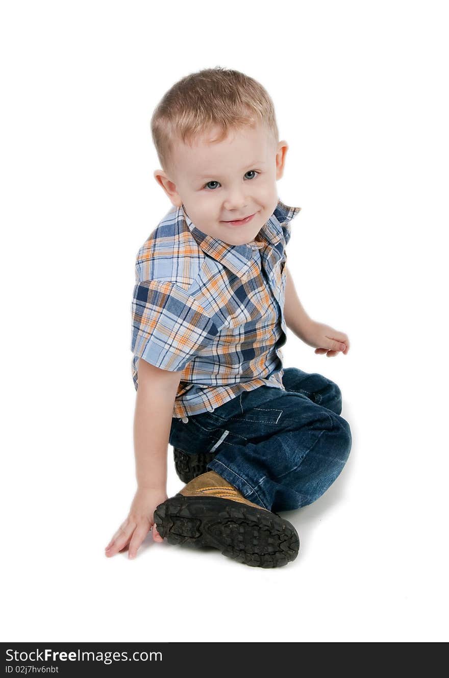 Smiling little boy sit on a floor, isolated on white