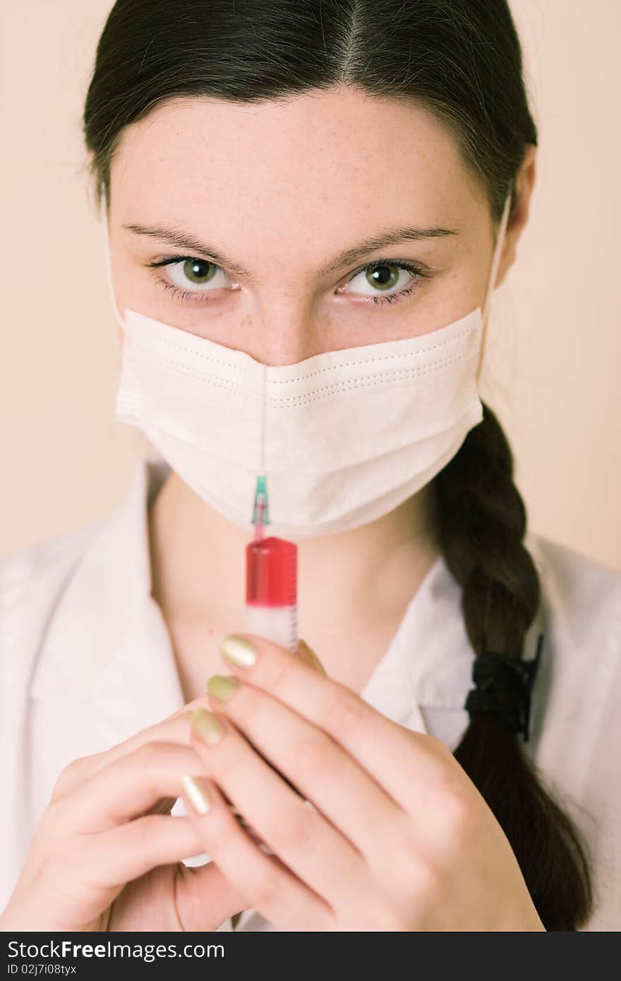 Portrait of young nurse or doctor with surgical face mask and syringe, studio background. Portrait of young nurse or doctor with surgical face mask and syringe, studio background.