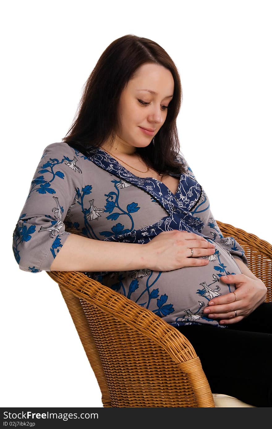 Pregnant woman sitting on a wicker chair and hugs belly, isolated on white. Pregnant woman sitting on a wicker chair and hugs belly, isolated on white