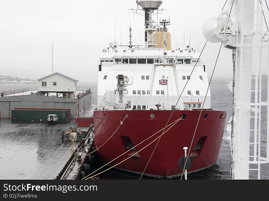 Red and white ship tied on dock