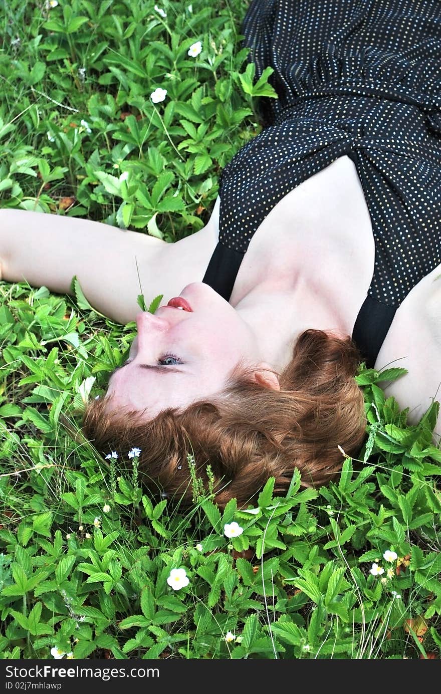 Young woman on glade in verdure of the strawberry. Young woman on glade in verdure of the strawberry