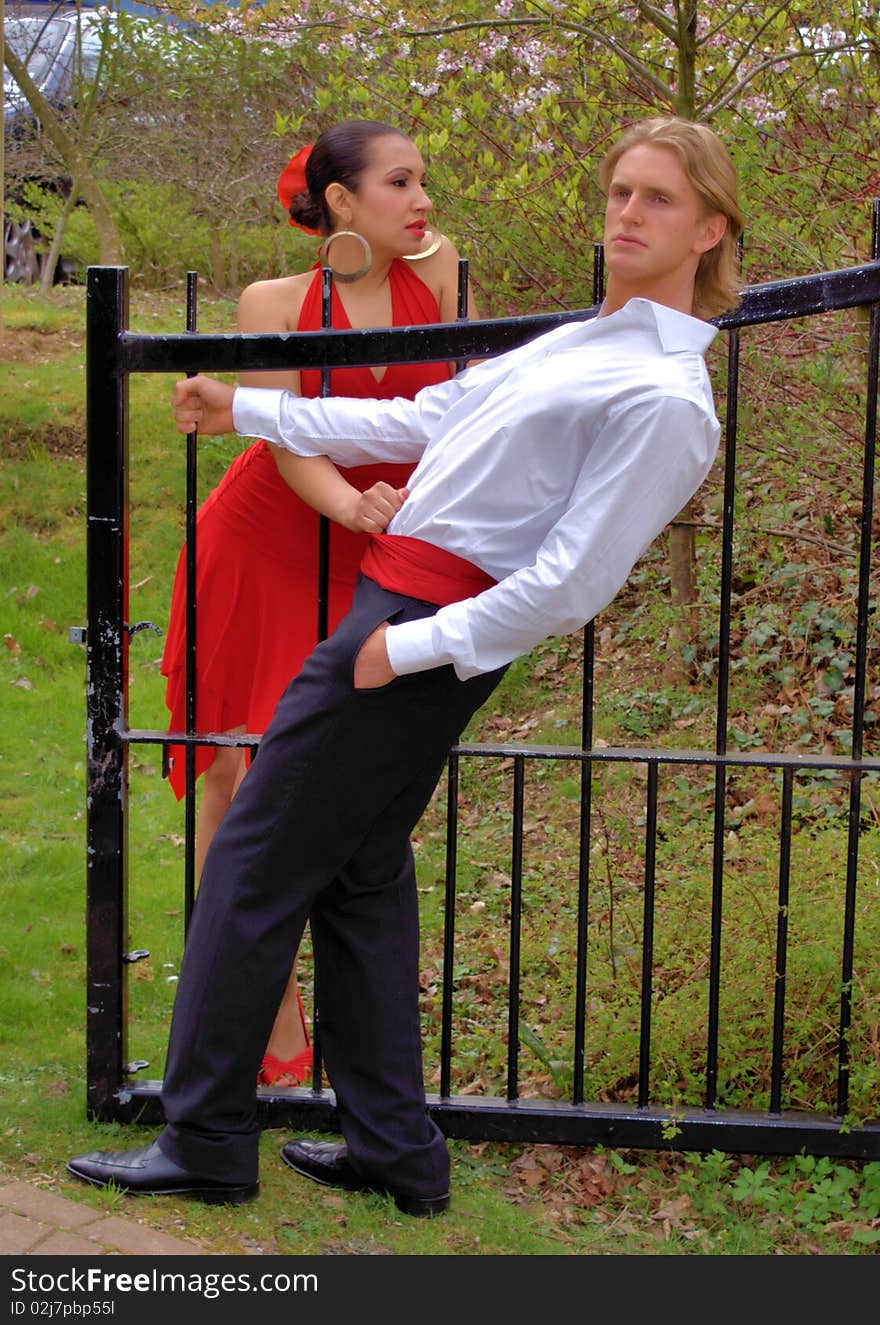 Man and woman flirting by the gate of a park. Man and woman flirting by the gate of a park