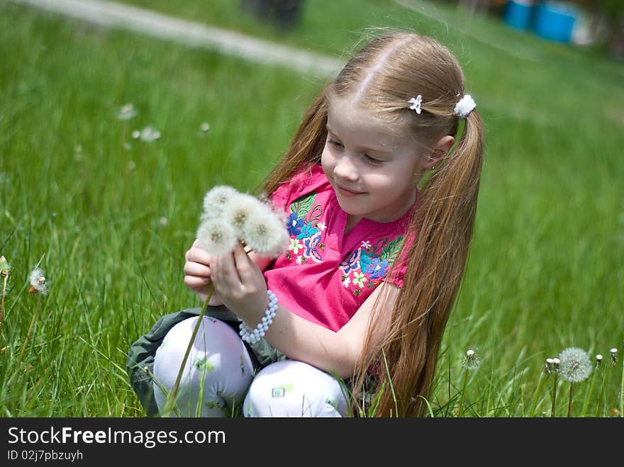 Smiling little girl on a green meadow with a bouquet of dandelions. Smiling little girl on a green meadow with a bouquet of dandelions