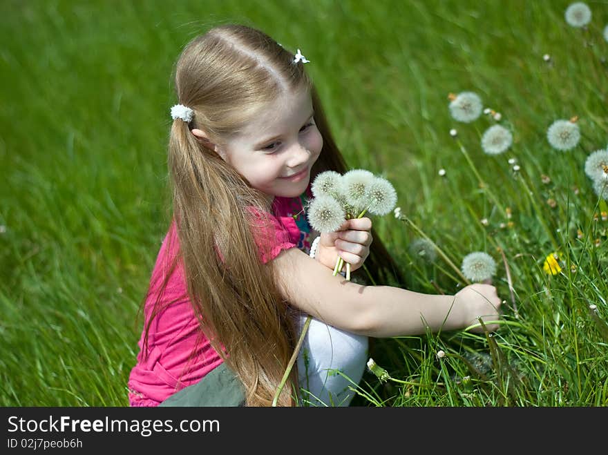 Smiling little girl on a green meadow with a bouquet of dandelions. Smiling little girl on a green meadow with a bouquet of dandelions