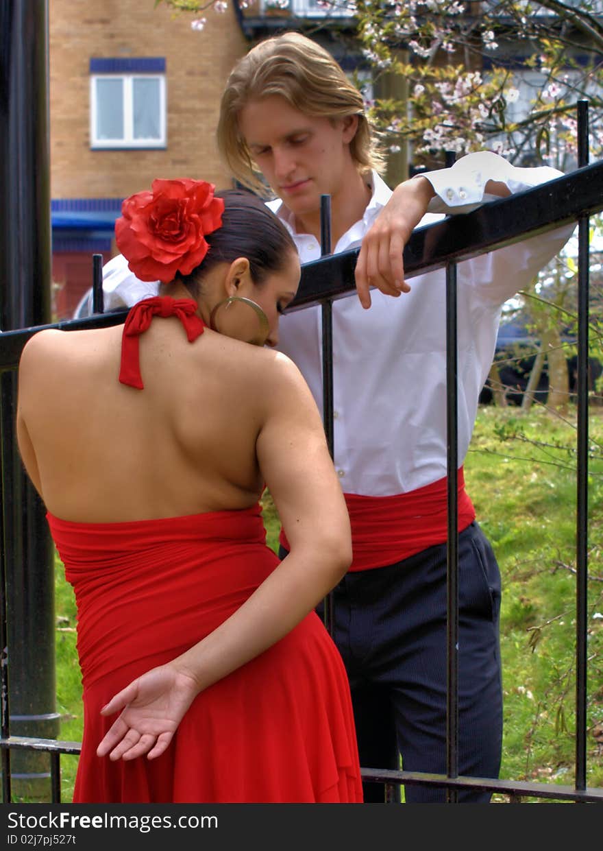 Man and woman flirting by the gate of a park. Man and woman flirting by the gate of a park