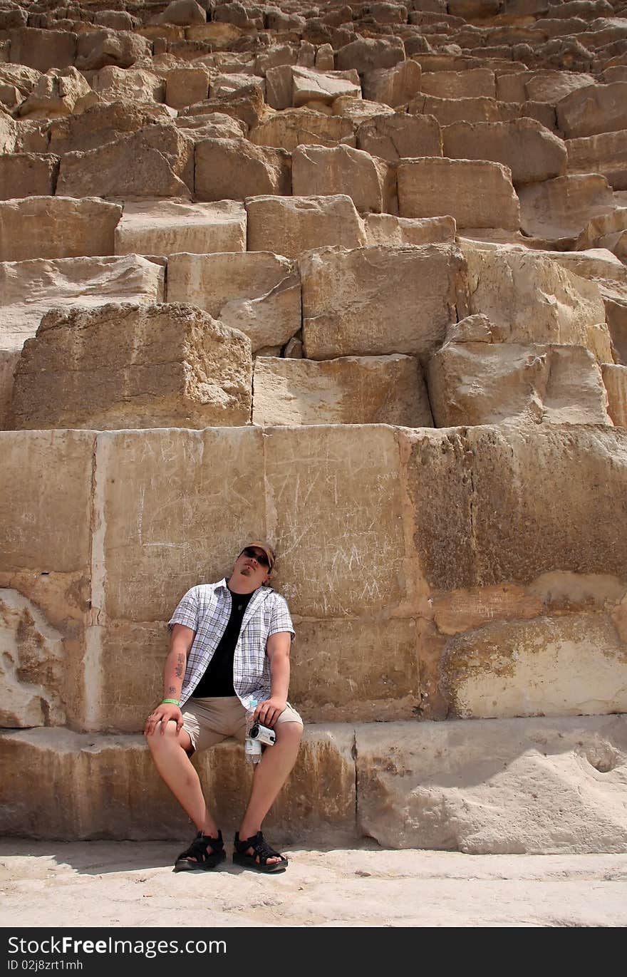 Tourist sitting at the bottom of the pyramides of Giza