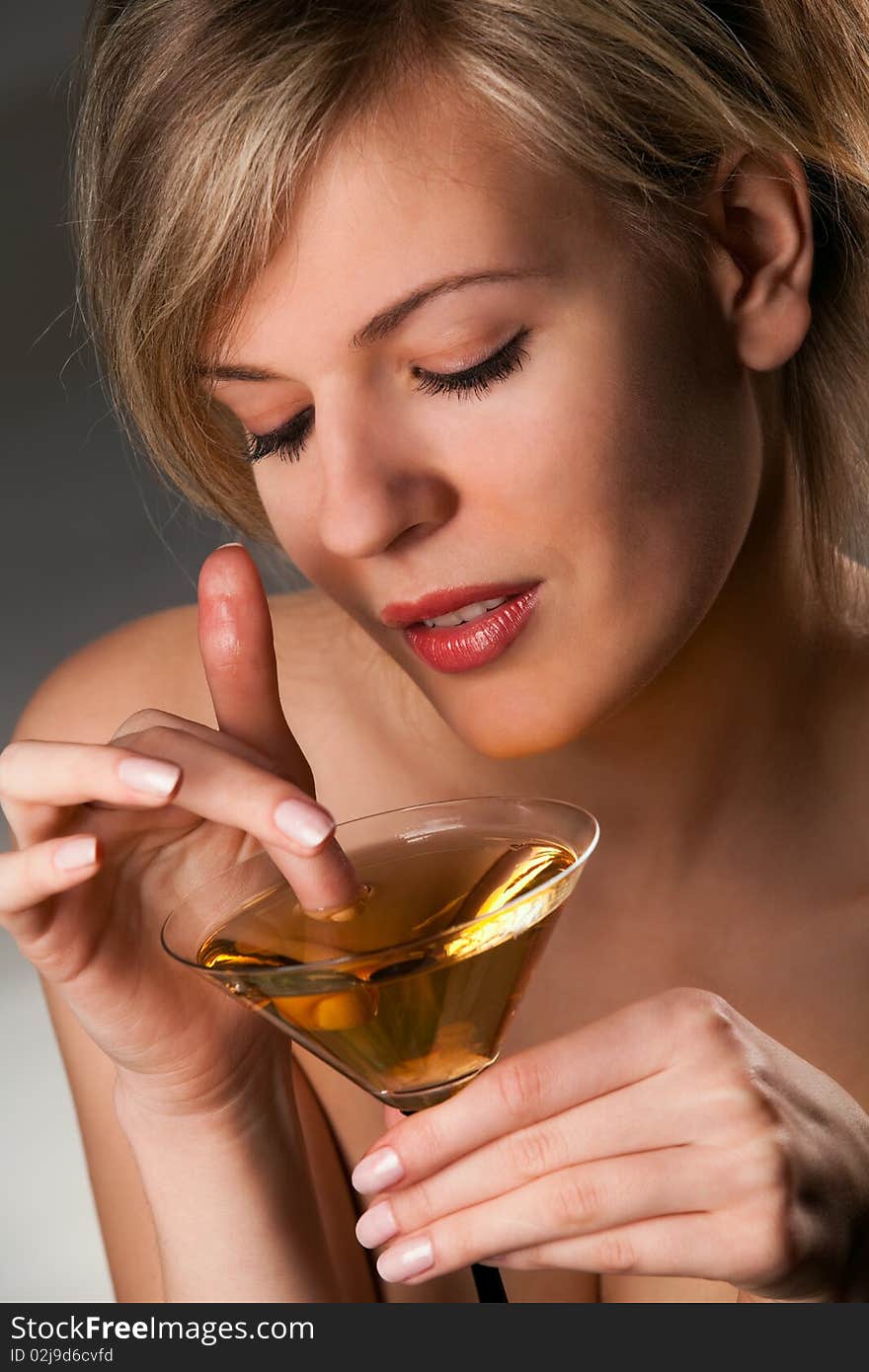 Beautiful woman with glass of cocktail going wool-gathering