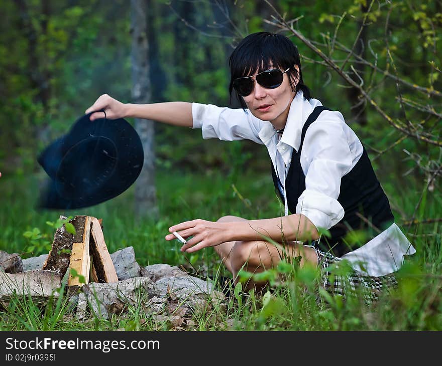 Woman like cowgirl in the forest near a campfire - stylization. Woman like cowgirl in the forest near a campfire - stylization