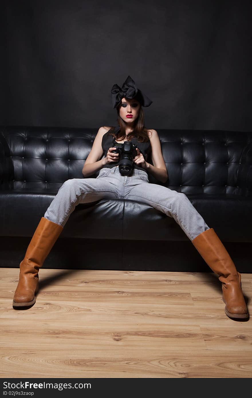 Young glamorous woman on a black sofa with photo camera at hands. Young glamorous woman on a black sofa with photo camera at hands.