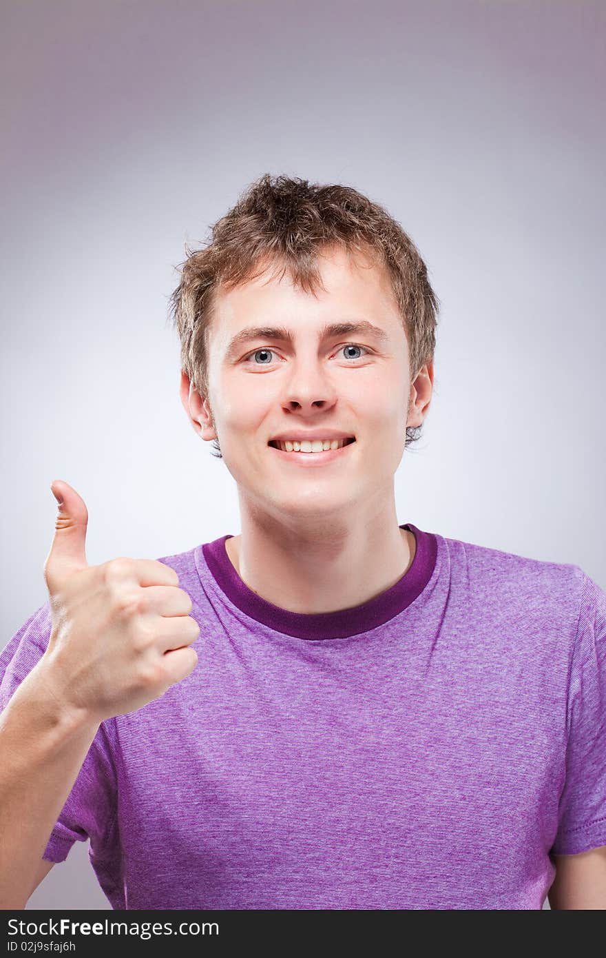 Portrait of handsome smiling young man, thumb up