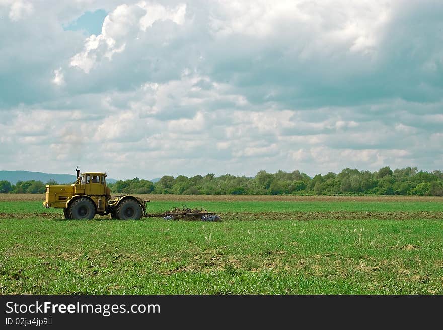 Working tractor under cloudy sky