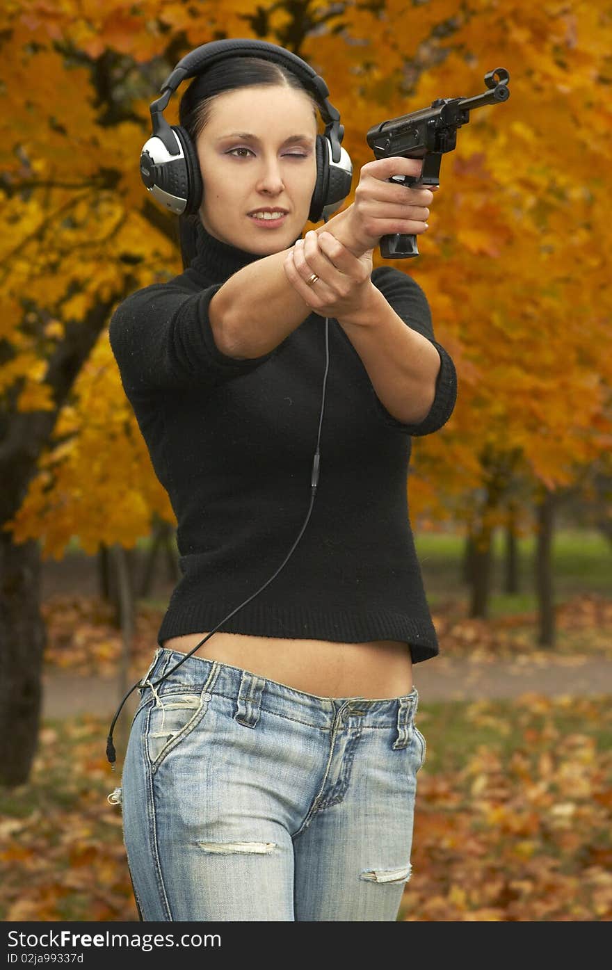 Girl  brunette in  headphones with  pistol