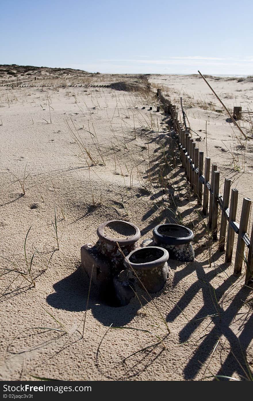 View of a section of a fence buried on the sand making a shadow. View of a section of a fence buried on the sand making a shadow.