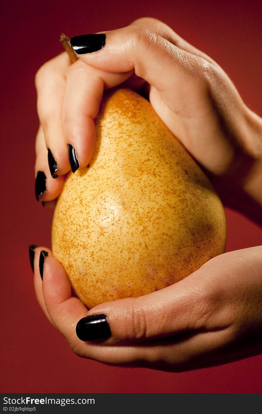 Close up view of two woman hands holding a pear. Close up view of two woman hands holding a pear.