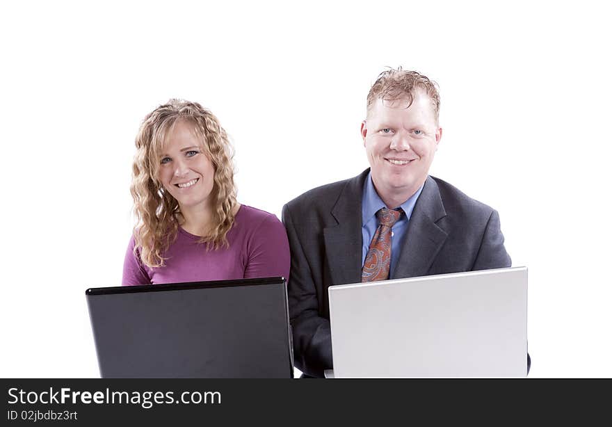 A man and a woman on computers sitting next to each other. A man and a woman on computers sitting next to each other.
