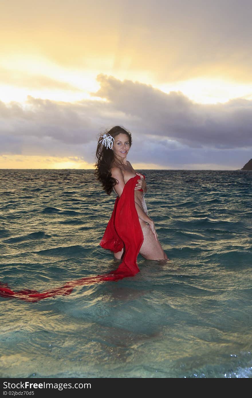 Forty year old woman in the ocean in chiffon at sunrise