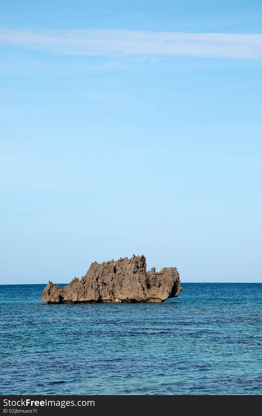 Scenic view of small rocky island in sea.