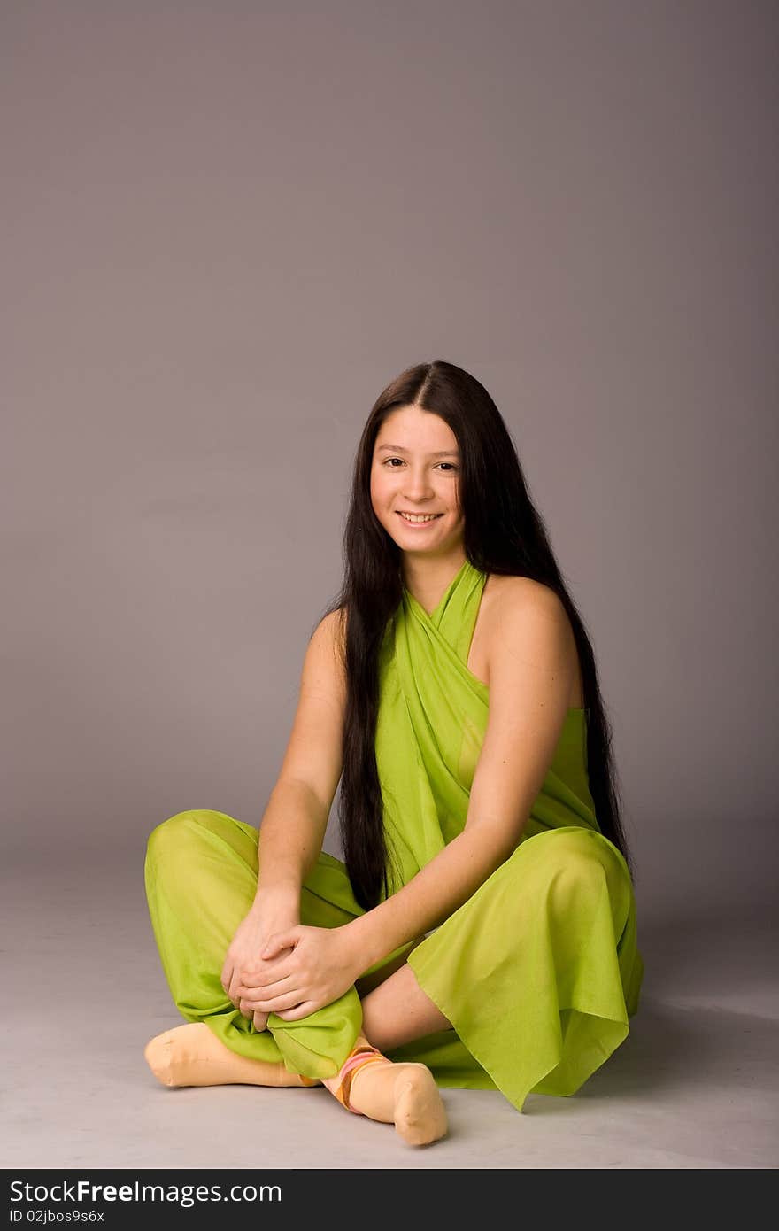 Attractive girl sitting on the floor - gray background