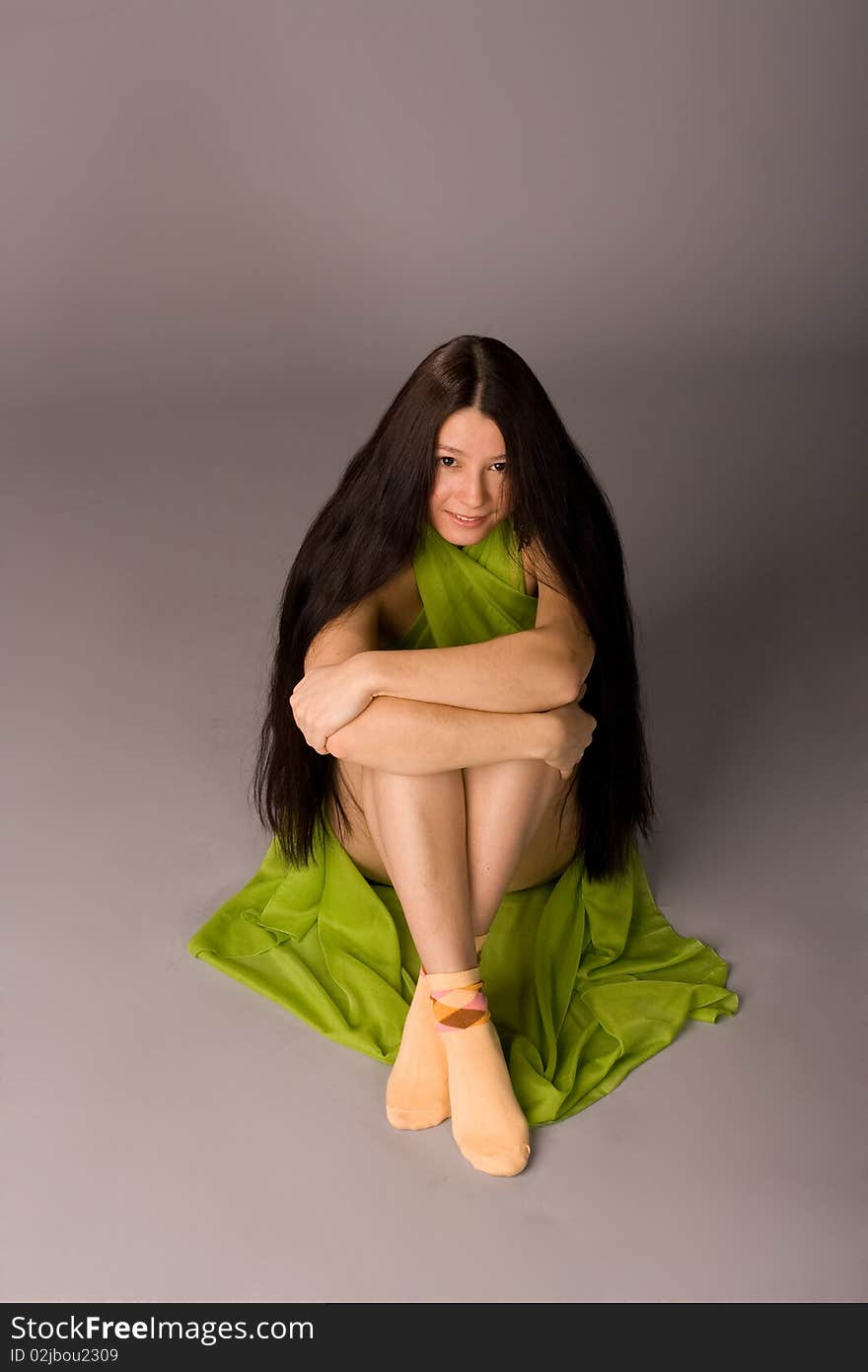 Attractive girl sitting on the floor - gray background