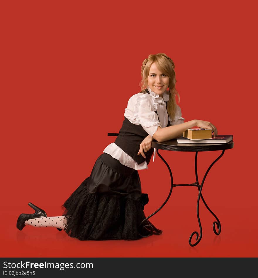 Attractive girl rests on the table with the books - a red background