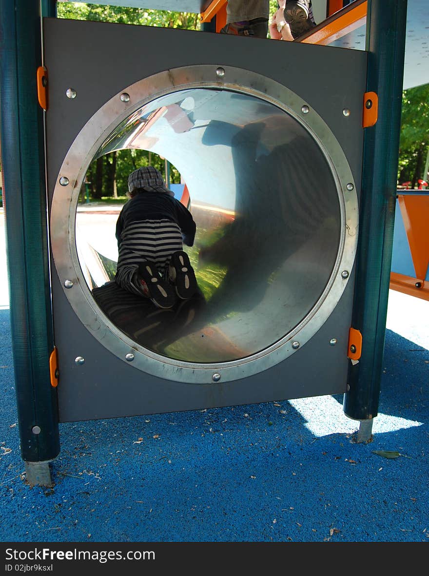 A child going through a tube at the playground. A child going through a tube at the playground