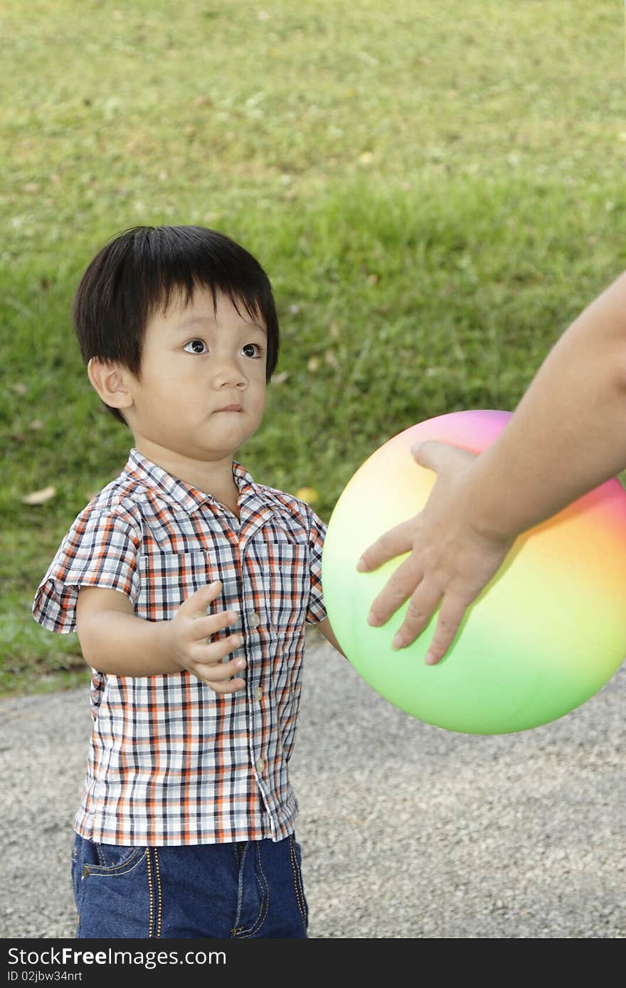 An Asian boy receiving a ball from his mother. An Asian boy receiving a ball from his mother