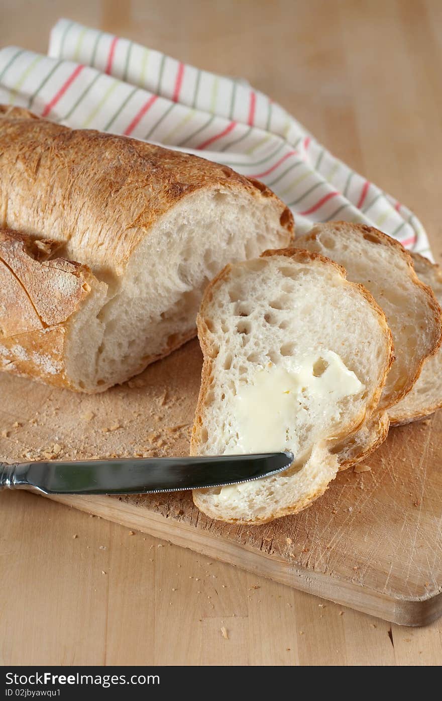 Partially Sliced Loaf of Bread on Wood Cutting Board and in brown paper bag