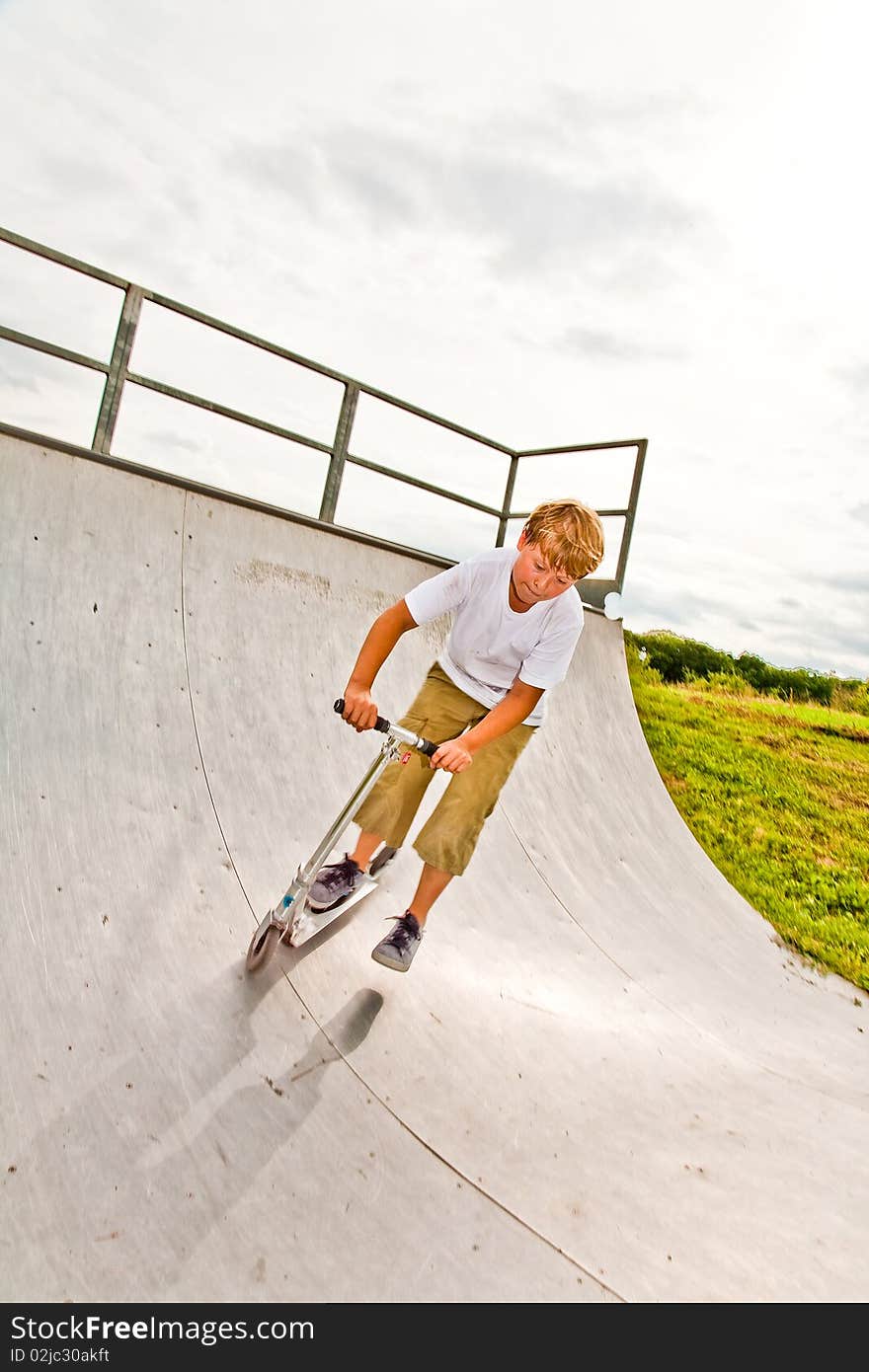 Child, boy has fun by doing tricks and jumping with scooter in the halfpipe. Child, boy has fun by doing tricks and jumping with scooter in the halfpipe