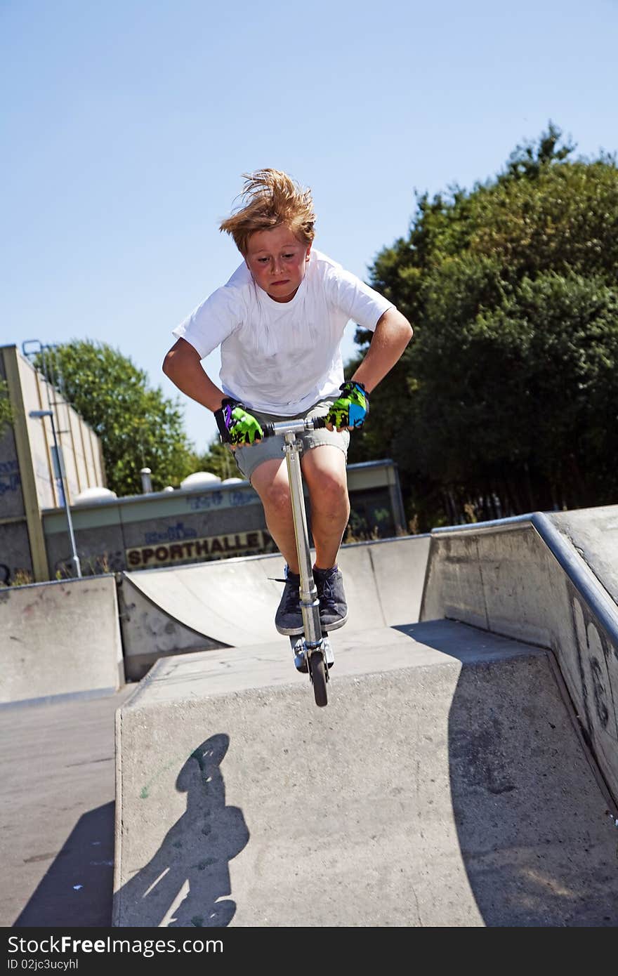 Boy rides scooter in a pipe at a skate park