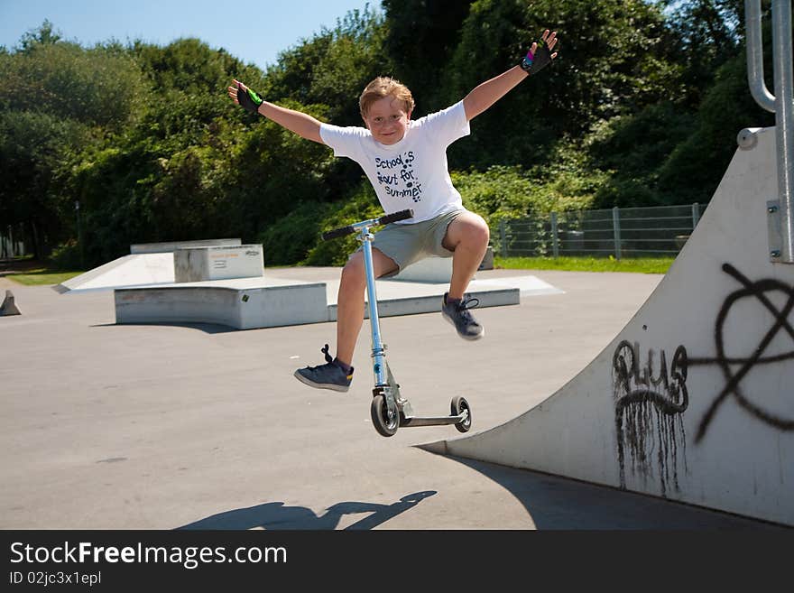 Boy rides scooter in a pipe at a skate park