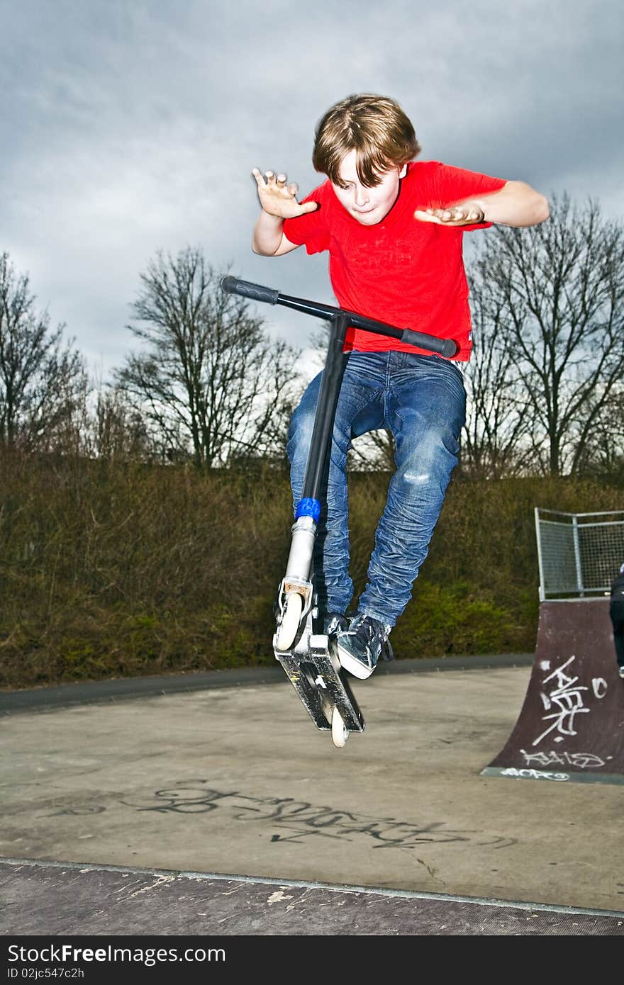 Boy riding a scooter going airborne at a scooter park. Boy riding a scooter going airborne at a scooter park