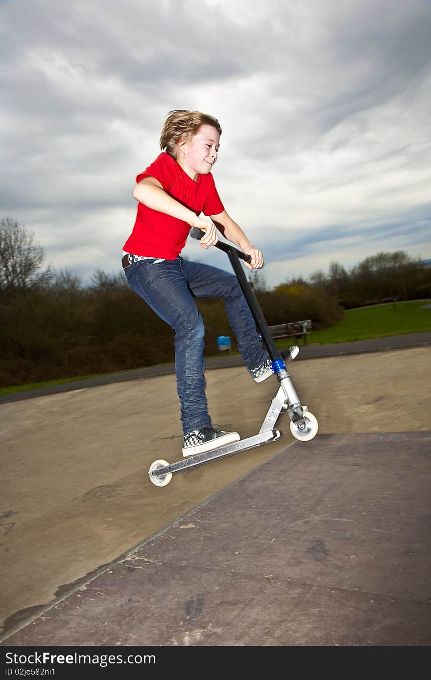 Boy riding a scooter going airborne at a scooter park. Boy riding a scooter going airborne at a scooter park