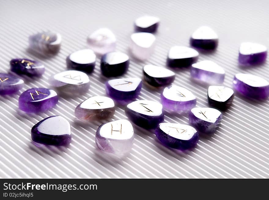 Beautiful violet stones with runes symbols over white background