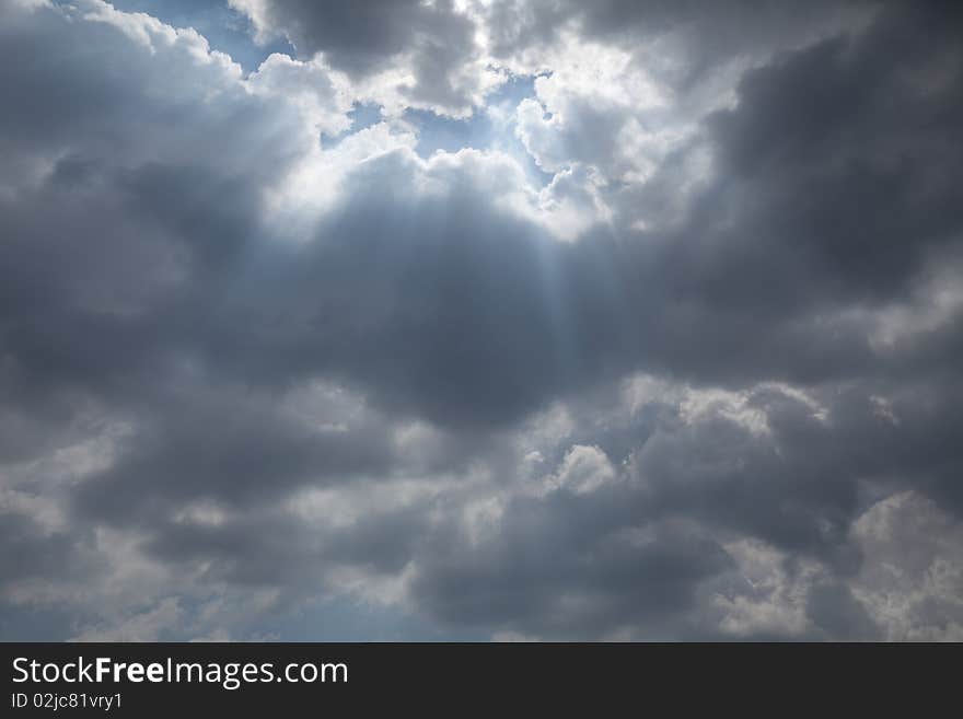 Sun ras, blowing up through clouds in sky