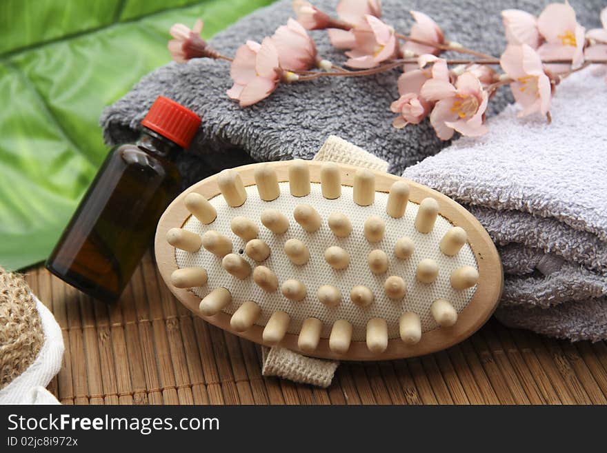 Massage brush with bottle and towel on mat