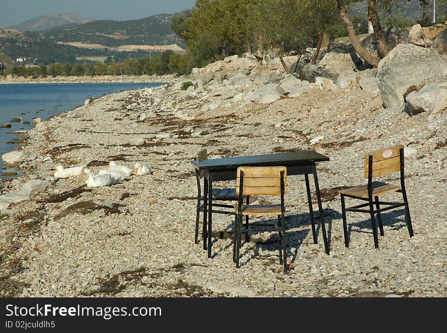 Lake and abandonet seats and table on the beach