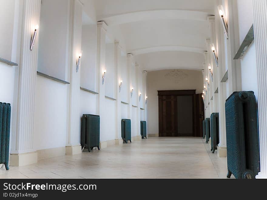 Empty corridor with lamps ending open door in a building