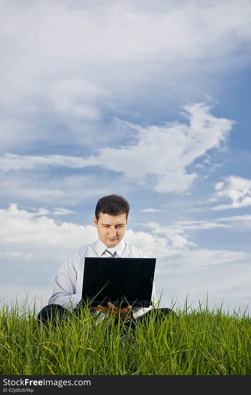 Businessman working in a meadow with laptop. Businessman working in a meadow with laptop