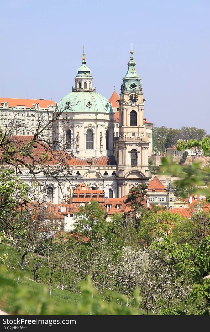 Prague's St. Nicholas' Cathedral with flowering trees and green grass