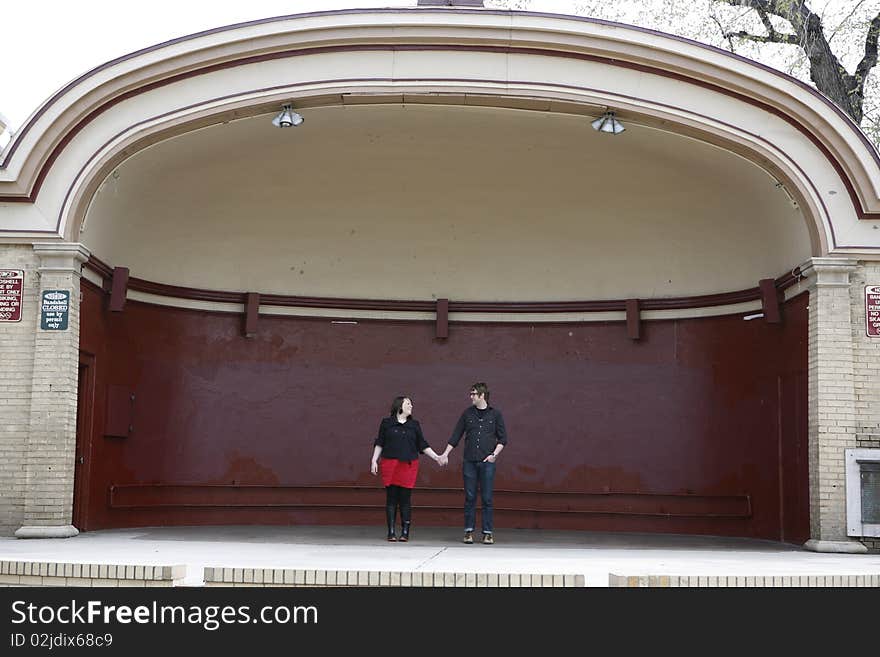 Young college age couple holding hands in love standing on outdoor stage. Young college age couple holding hands in love standing on outdoor stage