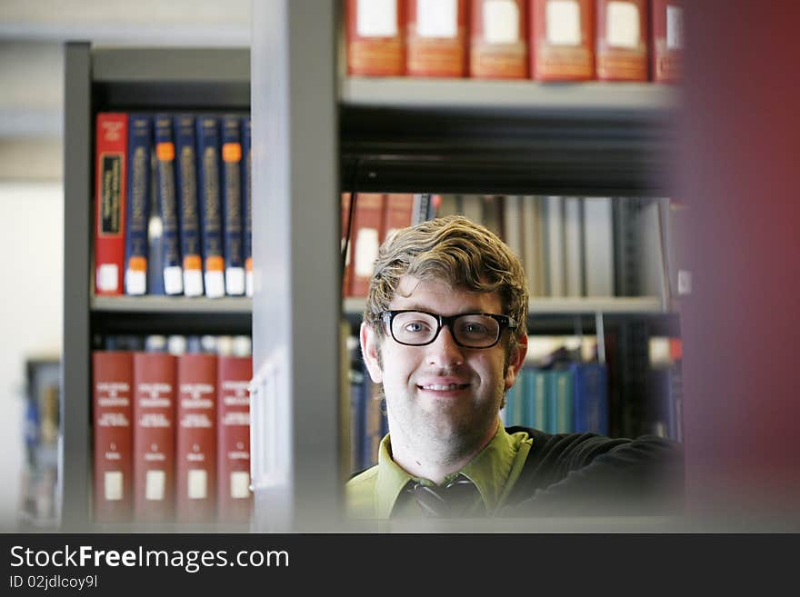 Male student with glasses in library smiling into camera