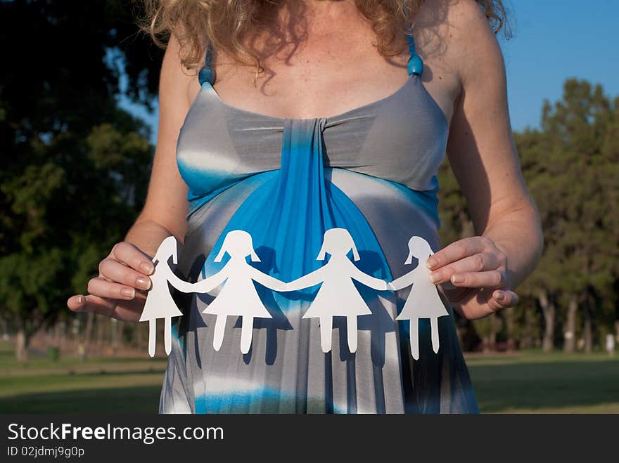 Pregnant woman holding small paper girls. Pregnant woman holding small paper girls