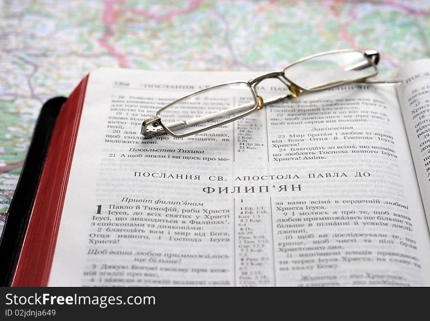 Bible in the Ukrainian language and glasses on map background. Bible in the Ukrainian language and glasses on map background