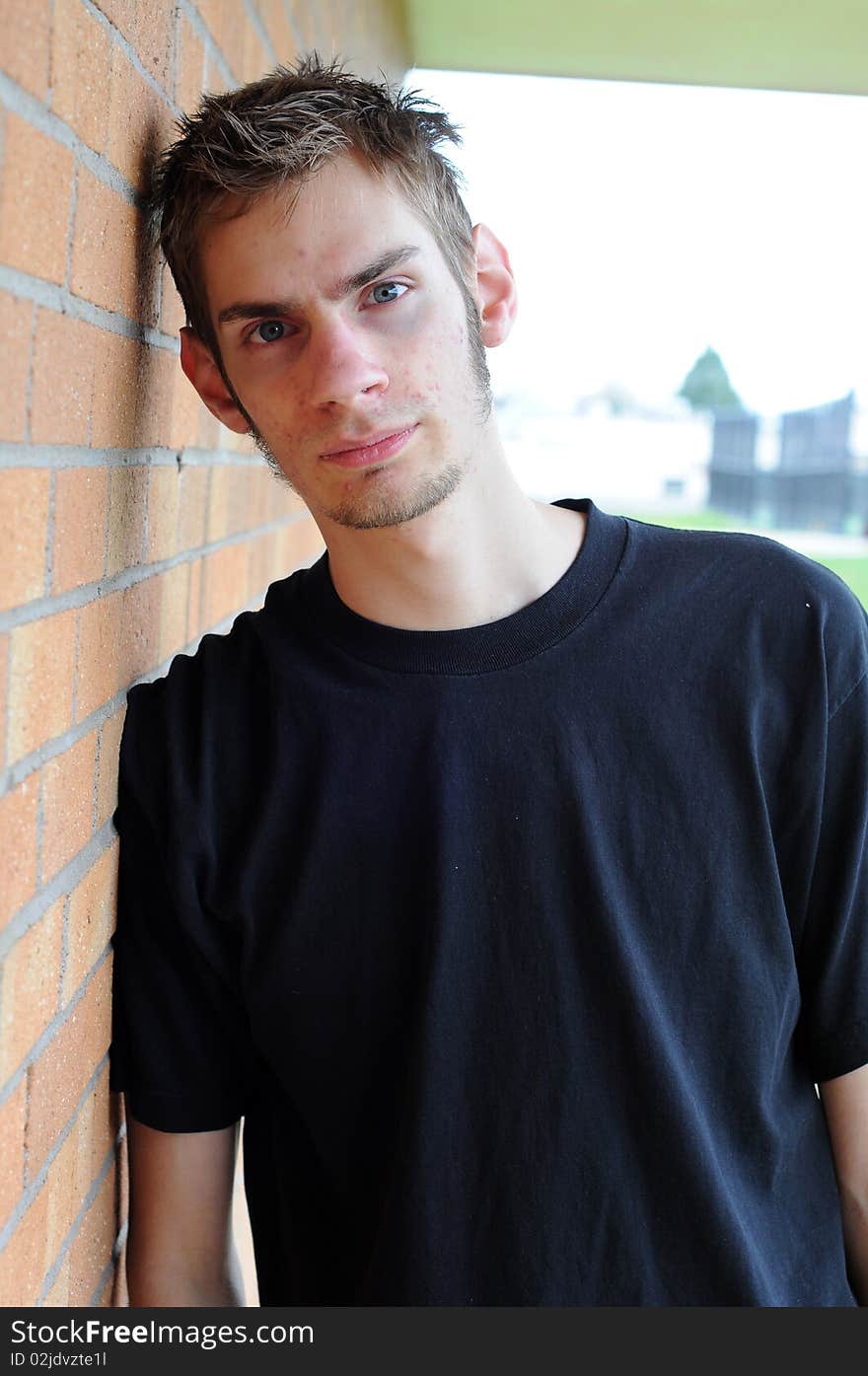 Student leaning against brick wall