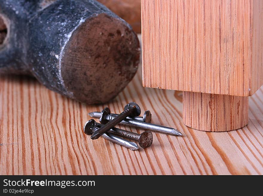 Nails on a wooden table with a hammer and a wooden product.