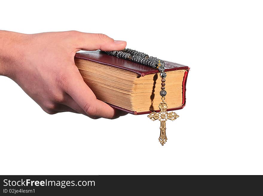 The man's hand holds the old bible with a cross on a chain.